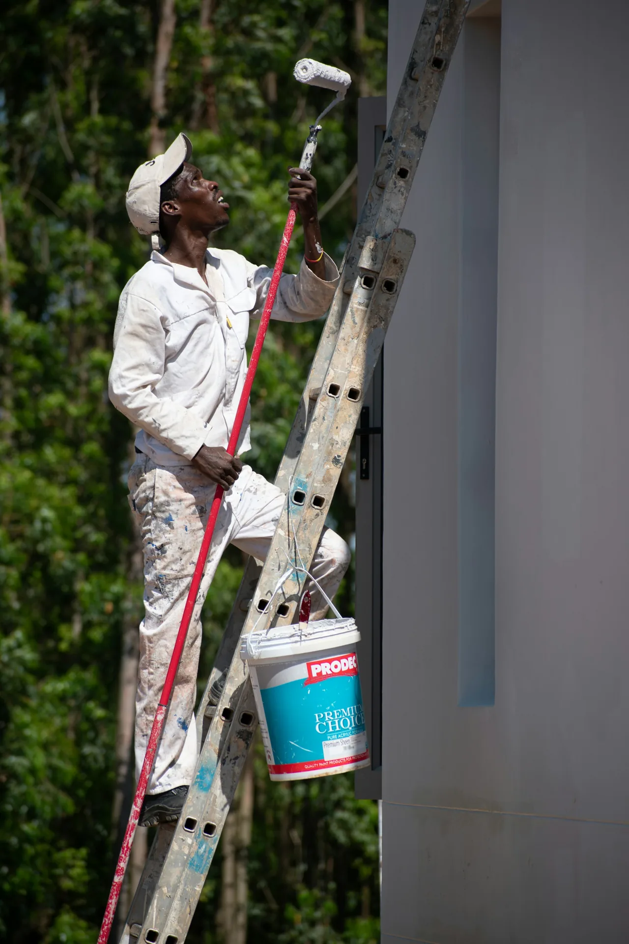 Painter on a ladder working on an exterior wall