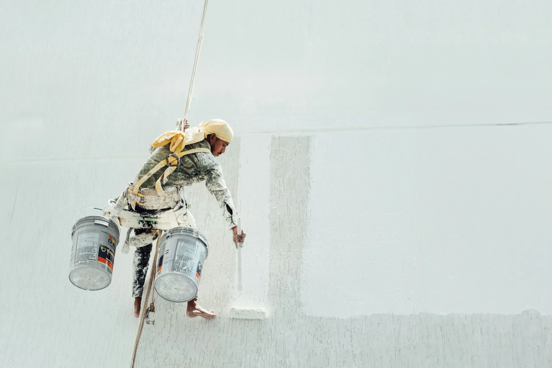 Painter applying an even white coat to a large wall